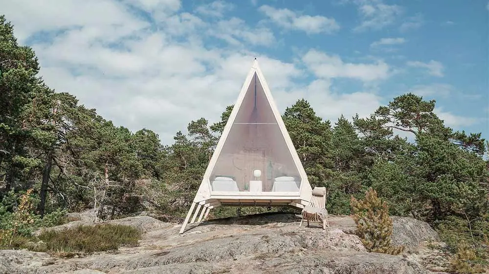 White A-frame shelter positioned among rocks and mountains